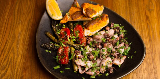 Photo of a plate with some shellfish prepared meat on wooden background.