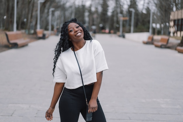 Photo portrait of cheerful black skinned girl in a city park. 