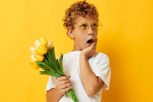 花の花束を持った白いTシャツを着た写真の肖像画の巻き毛の小さな男の子スタジオのライフスタイルは変更されていません