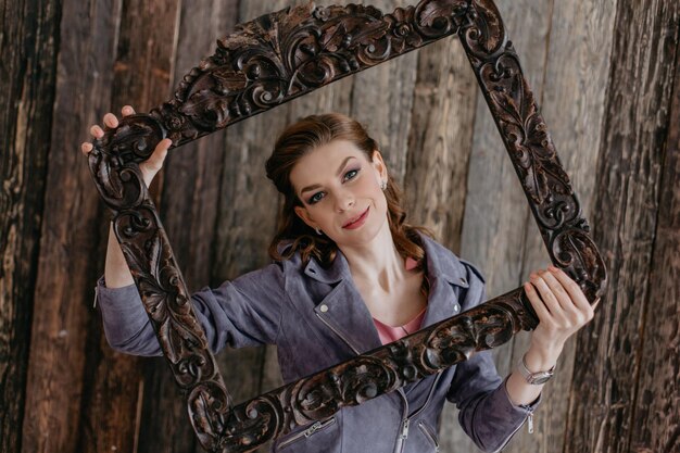 Foto ritratto fotografico di una carina giovane donna in una cornice di legno foto eccitata che indossa una elegante giacca viola