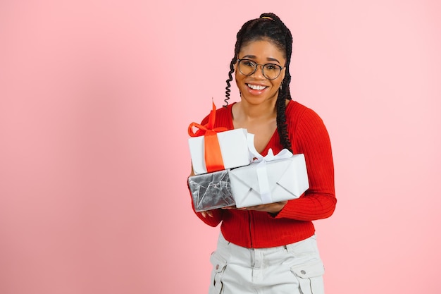 Photo portrait of excited woman holding gift box in two hands isolated on pastel pink colored background