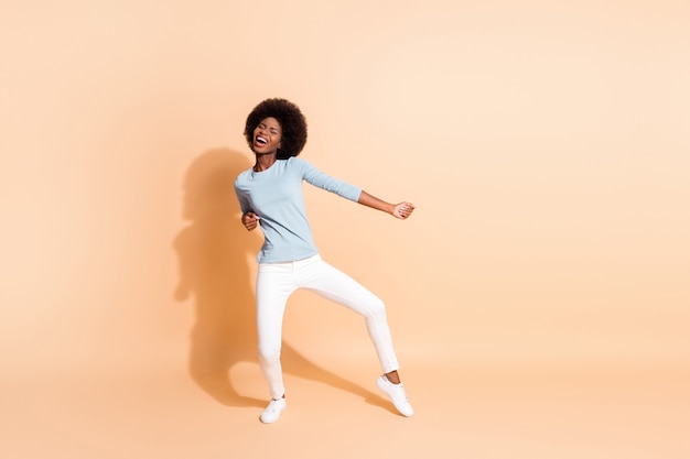 Photo portrait full body view of african american woman dancing enjoying party isolated on pastel beige colored background