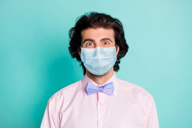 Photo portrait of guy smiling through medical safety mask isolated on pastel teal colored background