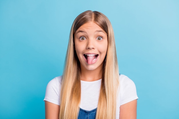 Photo portrait of playful kid showing tongue isolated on pastel blue colored background