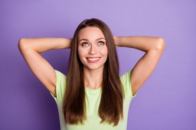 Photo portrait of relaxed girl with hands behind head looking up isolated on vivid purple colored background