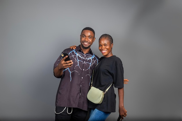 photo of positive excited people man and woman smiling and looking at their mobile phones isolated over gray background