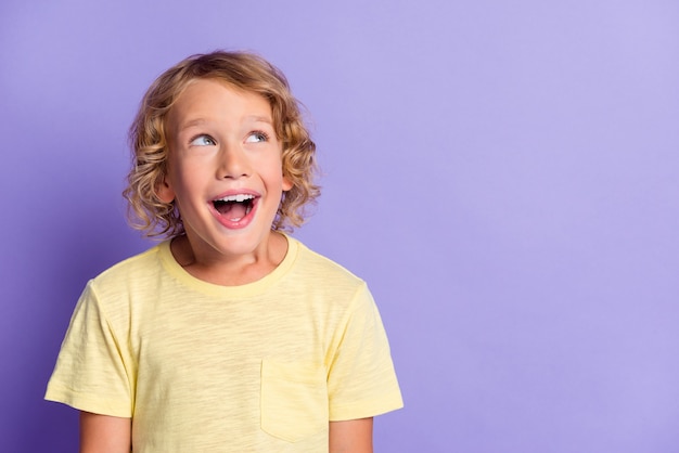 Foto di un ragazzo positivo e divertente che sembra ispirato nello spazio vuoto isolato su uno sfondo di colore viola