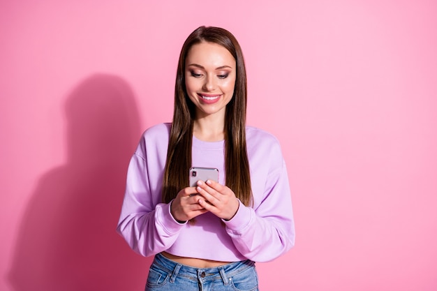 긍정적인 소녀가 휴대폰을 사용하는 사진 소셜 네트워크 뉴스 게시물 댓글 공유 재게시 파스텔 색상 배경 위에 격리된 바이올렛 데님 청바지를 입은 사진