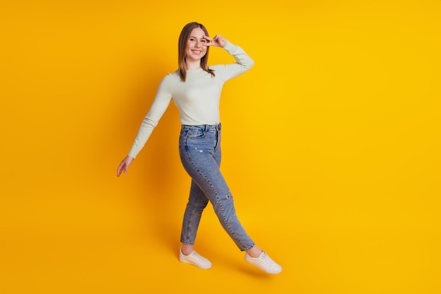 Foto di una splendida signora positiva che si gode la passeggiata indossando una camicia verde isolata su sfondo giallo