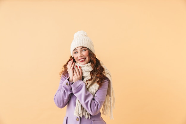 Photo of positive woman 20s in winter clothes smiling, while standing isolated 