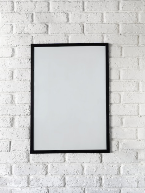 Photo photo of poster in a black frame on a white brick wall.