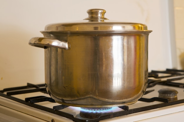 Photo of a pot on the flames of kitchen oven burning gas