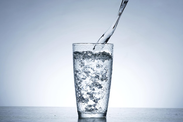 Photo of pouring water into a glass of water