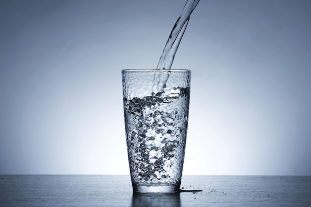 Photo of pouring water into a glass of water