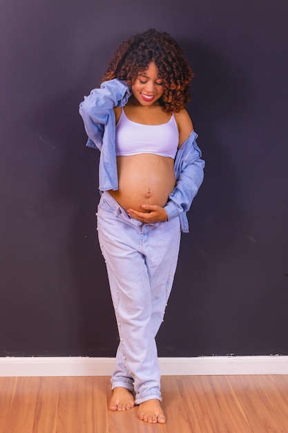 Foto di una donna afro americana incinta realizzata in studio fotografico con sfondo nero