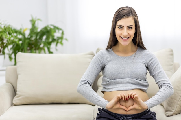 Photo of pregnant woman making heart shape with hands