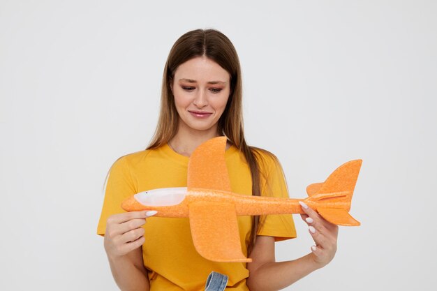 Photo pretty girl posing yellow airplane in the hands of fun isolated background