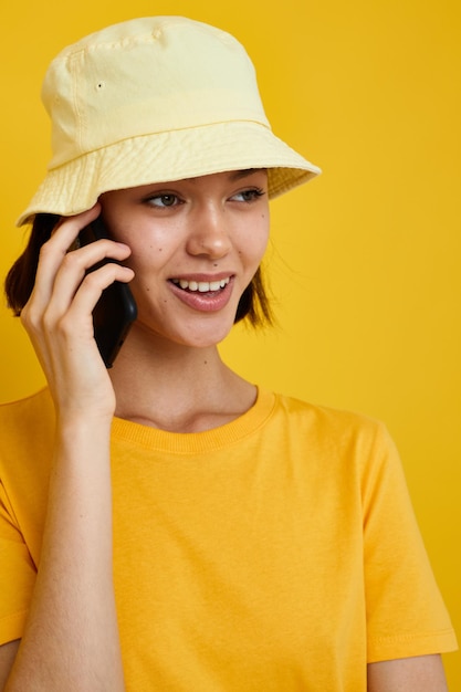 写真のかわいい女の子の黄色いTシャツと帽子の夏のスタイルと電話のライフスタイルは変更されていません