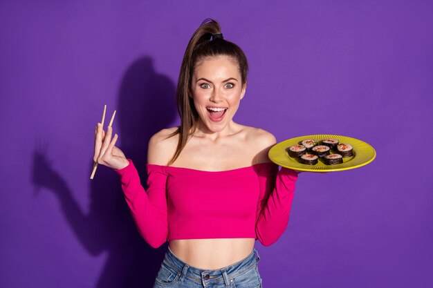 Photo of pretty lady hold chopsticks dish sushi excited opened mouth wear pin top isolated violet color background