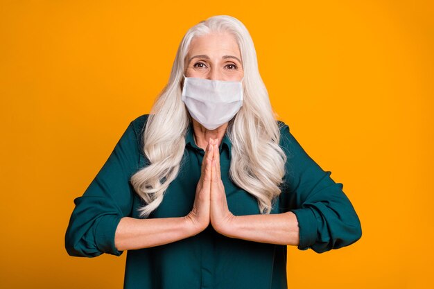 Photo of pretty lady holding hands together excited beg wear mask green shirt isolated bright yellow color background