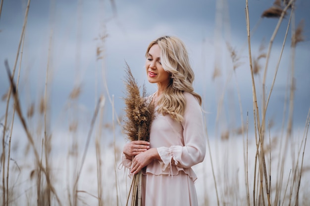 Photo of a pretty smiling girl with long blond curly hair in light long dress