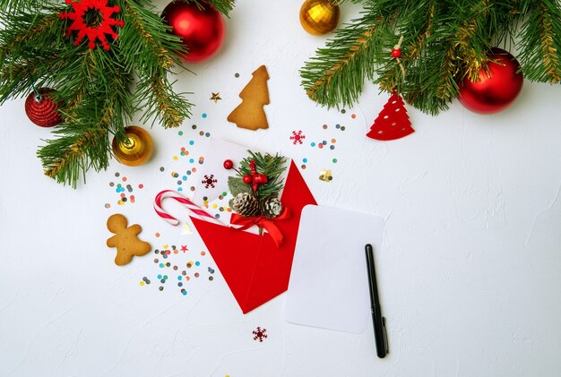 Photo of red envelope, cookies, branches of spruce Christmas decorations on empty white