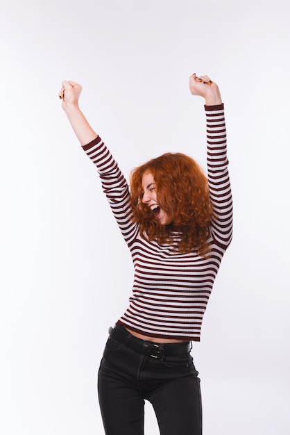 Photo of red head wung woman, celebrating and dancing over isolated background