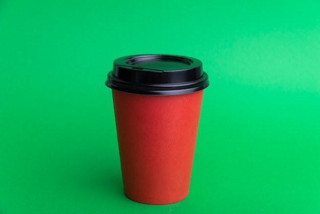 Photo of a red take away cup with black cap on green