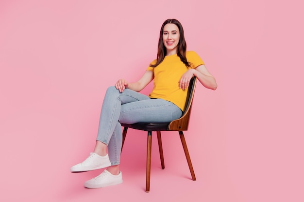 Photo photo of relaxed positive casual lady sit comfortable chair on pink background