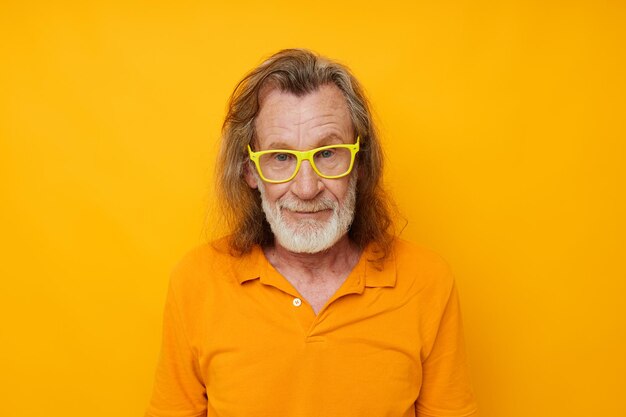 Photo of retired old man yellow tshirt and glasses posing yellow background