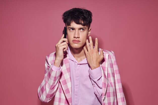 手に携帯電話を持つロマンチックな若いボーイフレンドの写真ピンクのブレザーファッションエレガントなスタイルのライフスタイルu ...