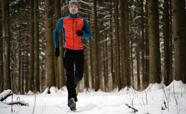 Photo of running athlete among trees in winter forest