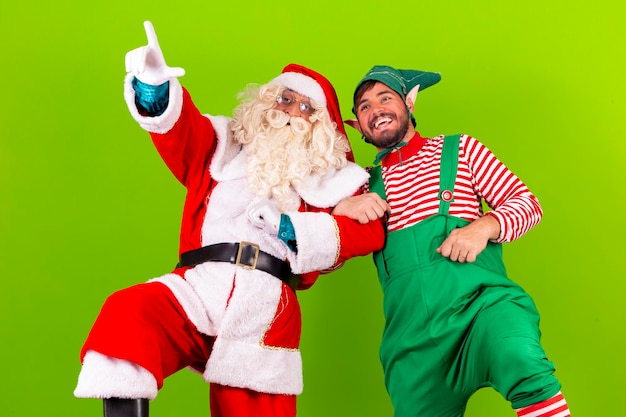 Foto foto di babbo natale su sfondo verde cromatico con il suo amico elfo