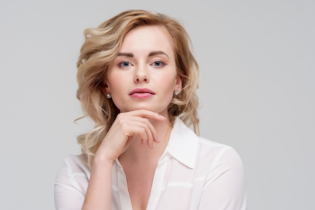 Photo of serious curly woman in white shirt in studio