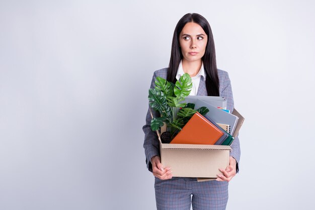 Photo of serious fear worker dismissed lady world financial crisis lost work hold carton box stuff fired quit look side empty space scared angry boss formalwear isolated grey color background