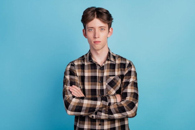 Photo of serious young man wear casual outfit confident crossed hands isolated on blue color background