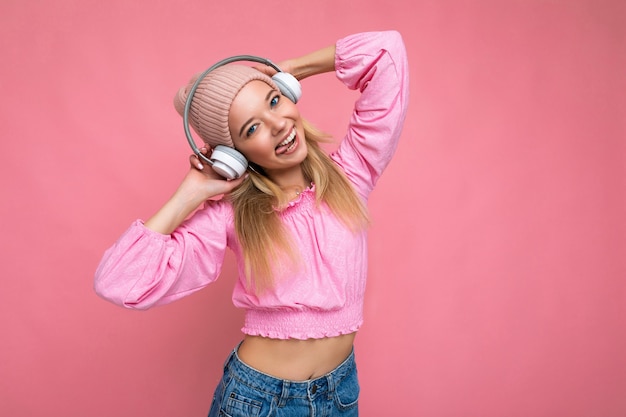 분홍색 블라우스와 분홍색 모자를 쓰고 섹시한 매력적인 긍정적 인 웃는 젊은 금발의 여자의 사진