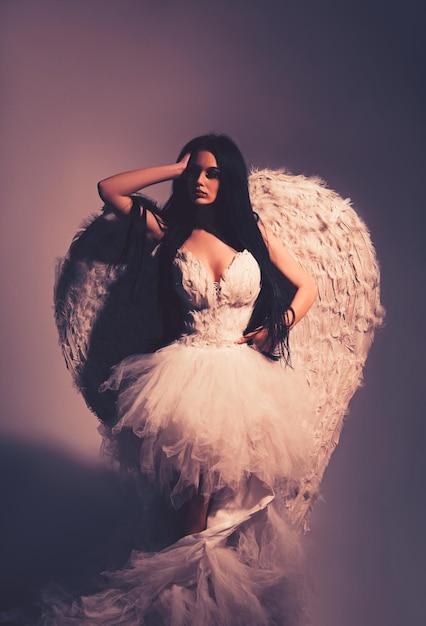 Photo of sexy brunette woman with long hair wearing angel's wings Beautiful body