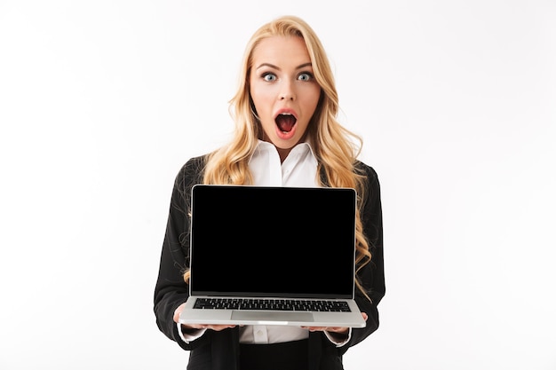 Photo of shocked businesswoman wearing office suit holding laptop with black screen, isolated