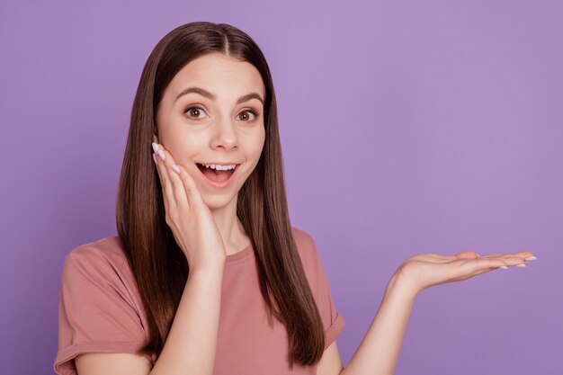 Photo of shocked lady holding product open hand offer isolated on purple background