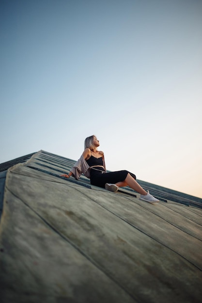 Foto sessione fotografica sul tetto giovane donna che posa sul tetto al tramonto persone stile di vita concetto di rilassamento