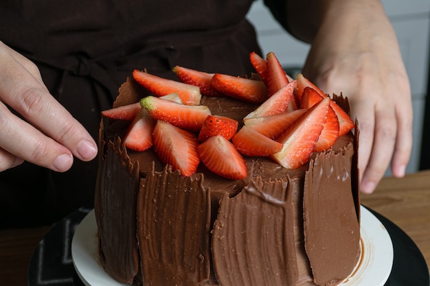 チョコレートケーキを飾った写真撮影。イチゴ、新鮮なバジルの葉、ブラックベリージャム、チョコレートプレートで覆われたチョコレートケーキ。