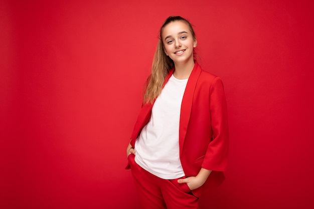 Foto scattata di bella bambina bruna sorridente felice che indossa giacca rossa alla moda e maglietta bianca