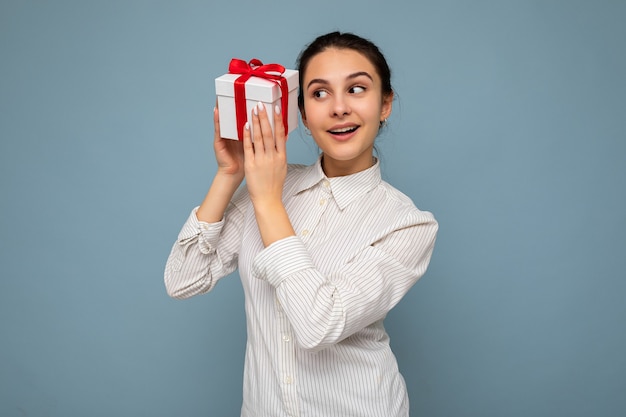 Photo shot of beautiful happy smiling brunette young woman isolated over blue background wall