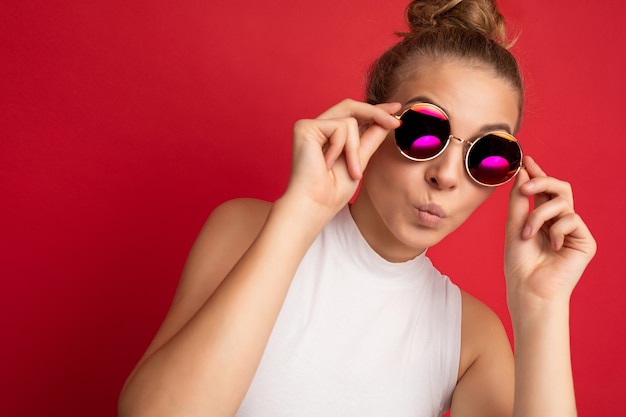 Photo shot of beautiful young blonde woman wearing casual clothes and stylish sunglasses