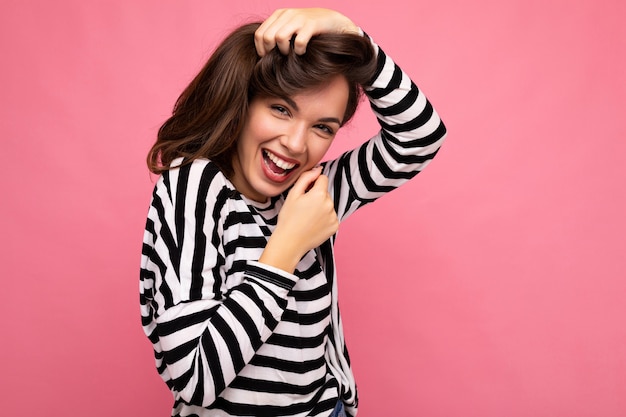 Photo shot of cute attractive pretty positive happy young brunette woman wearing casual striped longsleeve isolated over colorful background with copy space