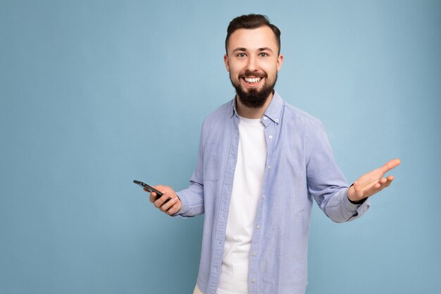 Photo shot of handsome smiling positive good looking young man wearing casual stylish outfit