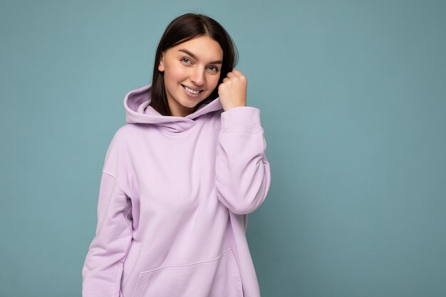 Photo shot of pretty joyful smiling young female person wearing casual trendy outfit standing isolated on colourful background with copy space looking at camera and having fun.