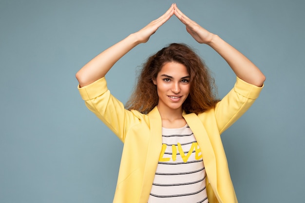 Photo shot of young positive happy beautiful brunette curly woman with sincere emotions wearing