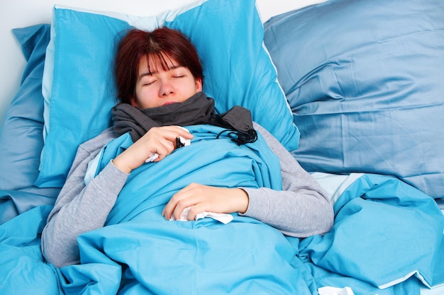Photo of sick woman in scarf lying on bed